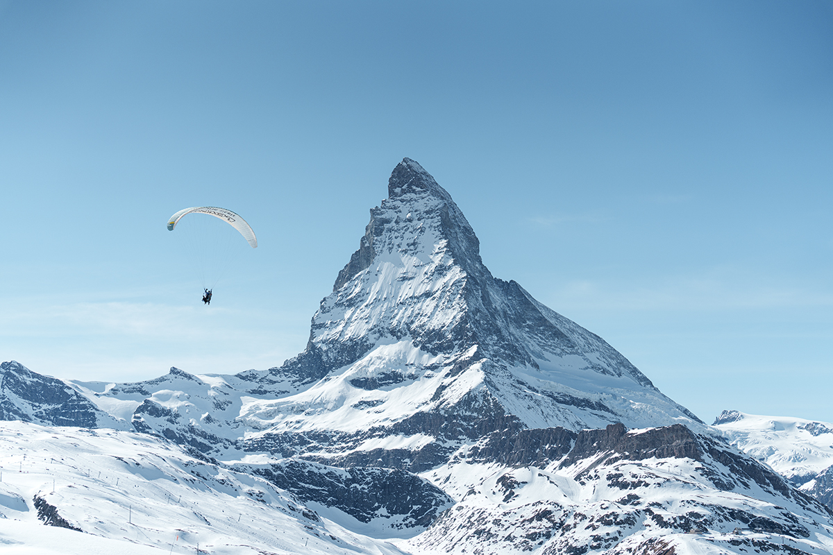 Winteraufnahme des Matterhorns mit Paraglider am Himmel.